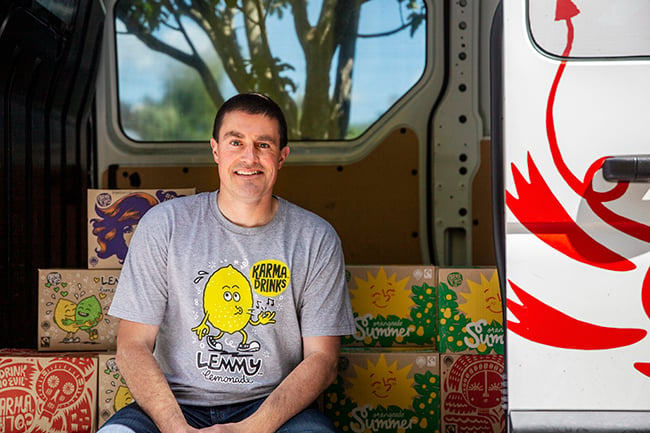 Patrick Coyle from Karma Cola sitting on a truck next to some drinks