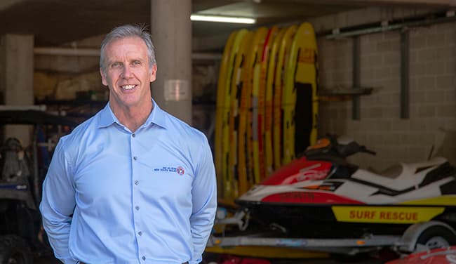 Steven Pearce from Surf Life Saving NSW standing in the boat shed in front of a jetski