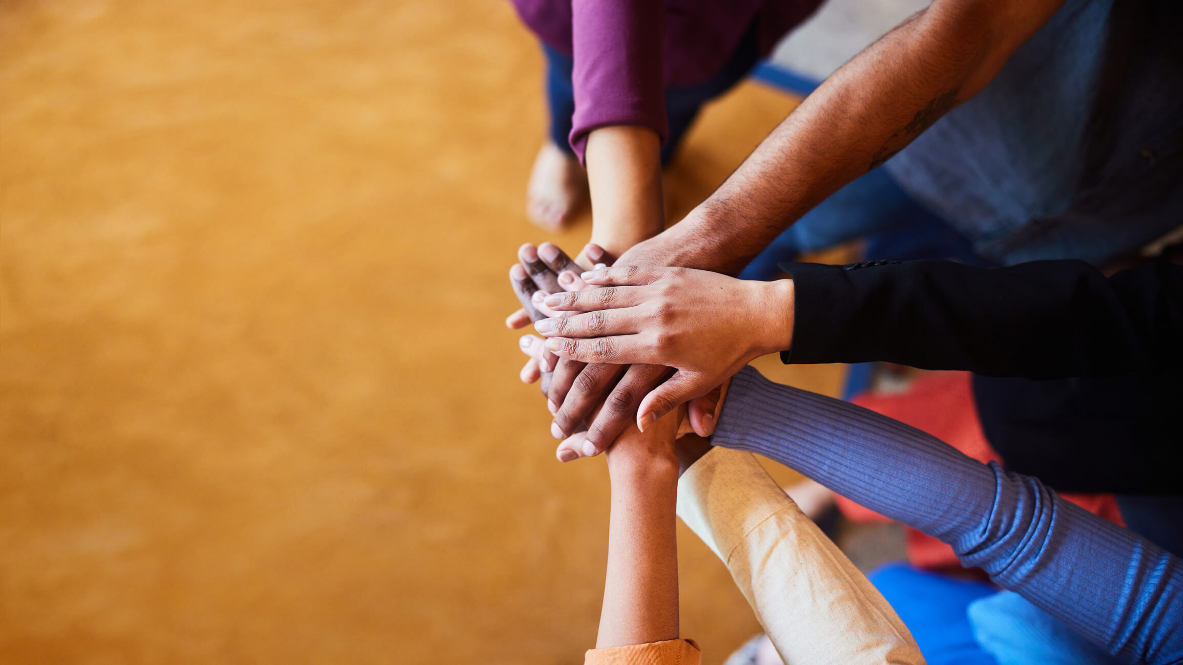 High angle view of a group of diverse businesspeople standing in a semi circle with their hands in a pile in an office